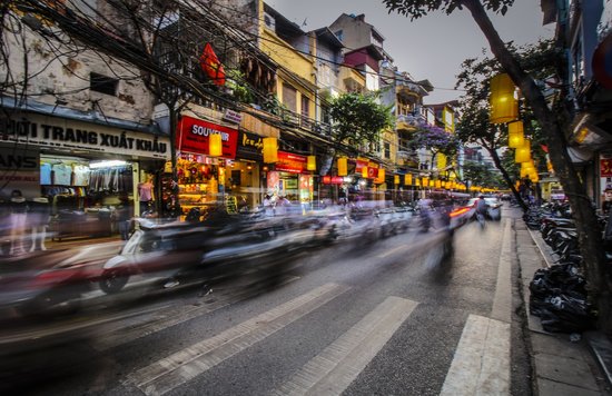 Busy Hanoi Old Quarter street with motorbikes, shops, and glowing lanterns