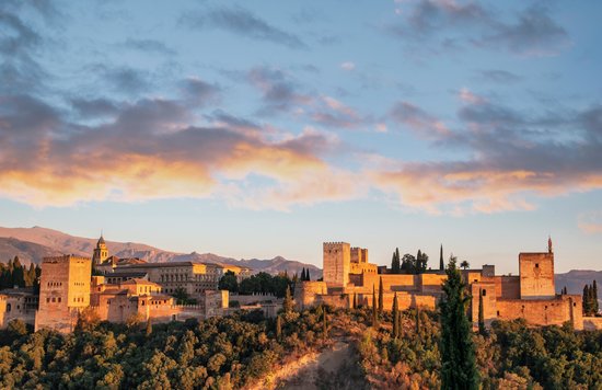 Alhambra palace glowing at sunset with the city of Granada below