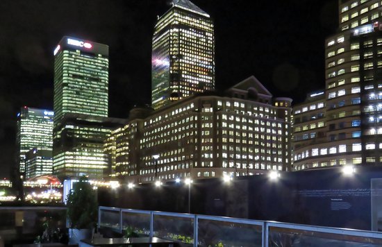 Night skyline view from a rooftop bar in the UK with illuminated buildings