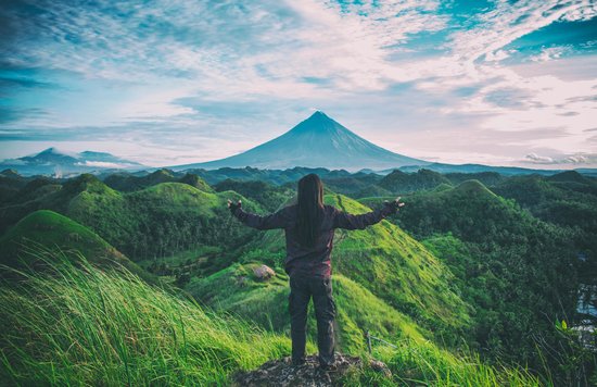 Solo traveler standing on a hilltop, embracing freedom and calm during an introverted solo journey | Photo from Archie Binamira on Pexels