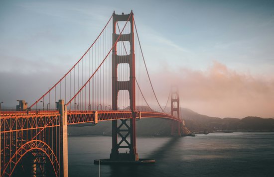 Golden Gate Bridge in San Francisco stretching over water with light fog