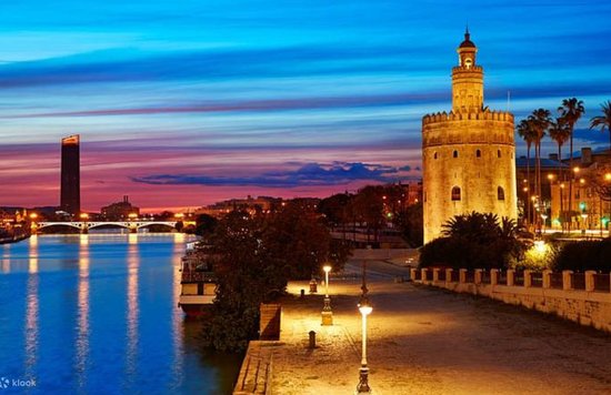 Torre del Oro and Guadalquivir River at sunset in Seville with colorful evening sky.