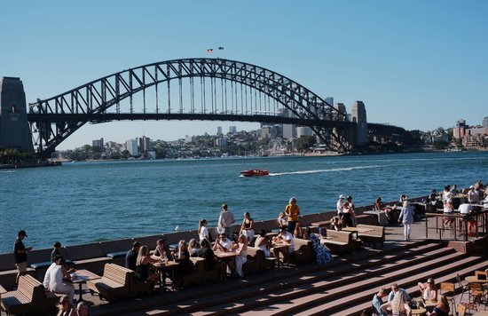 People dining by Sydney Harbour with the Harbour Bridge in the background