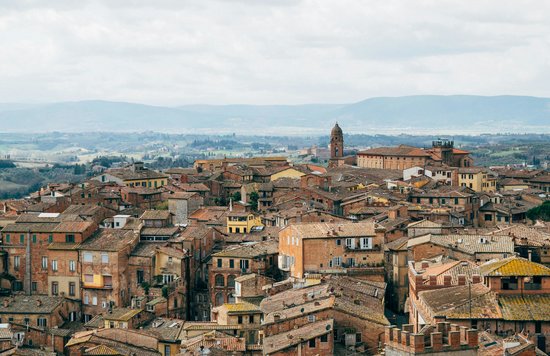Aerial view of historic Italian town with terracotta rooftops and rolling hills