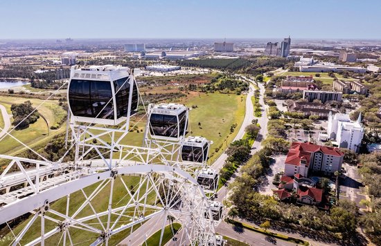 Close-up of The ICON observation wheel cabins with a wide view of Orlando’s skyline and roads below