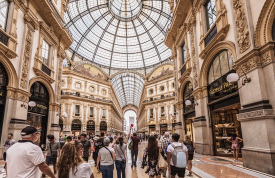 Tourists walking inside Galleria Vittorio Emanuele II glass dome arcade Milan