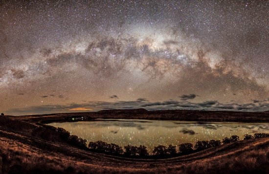 Lake Tekapo night sky with Milky Way and stars reflecting on calm water