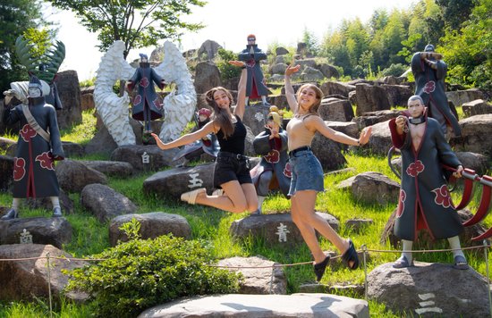 Visitors posing with Naruto anime character statues outdoors
