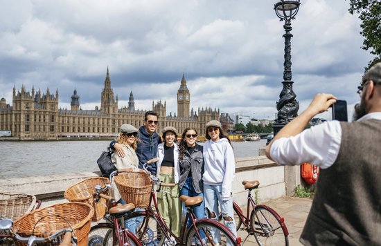 Group on a bike tour posing by the Thames with Big Ben and Houses of Parliament in London