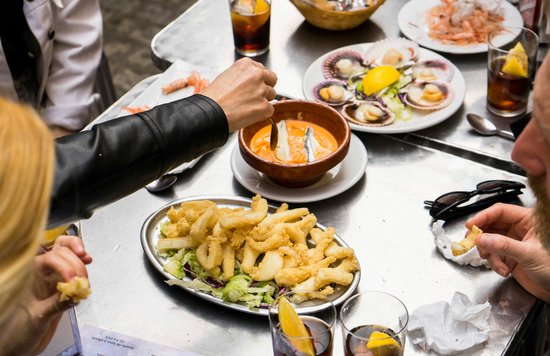 Friends enjoying tapas and drinks around a restaurant table in Seville