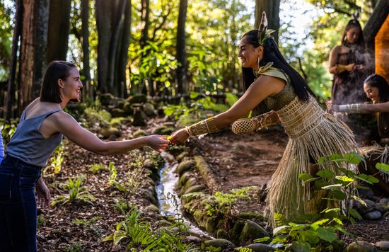 A Māori guide greets a visitor in a forest cultural village experience in Rotorua