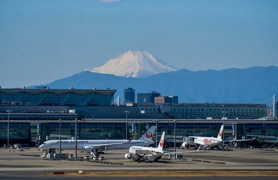 Airplanes on an airport runway in a Japan terminal with a view of Mount Fuji