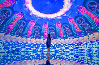 A visitor stands inside a brightly lit blue and purple immersive room at House of Hype Dubai.