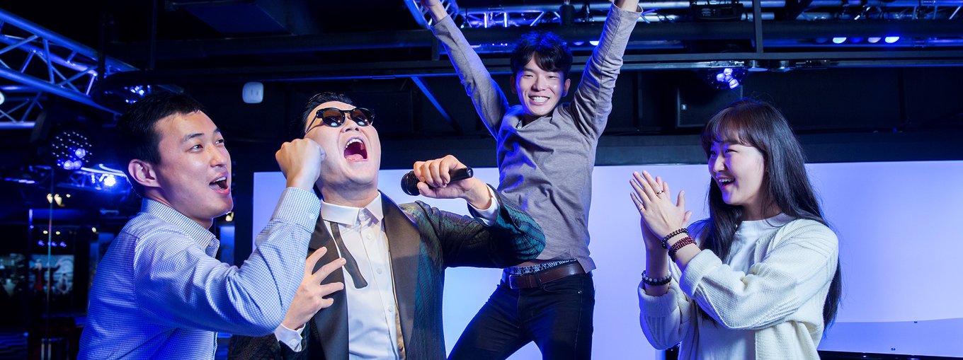 Two men and a woman happily posing for a photo with PSY's wax figure