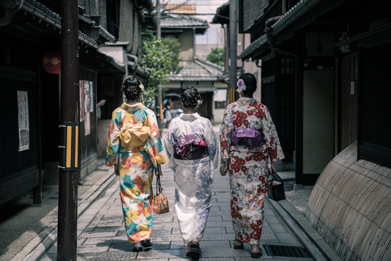 three geishas walking in japan streets