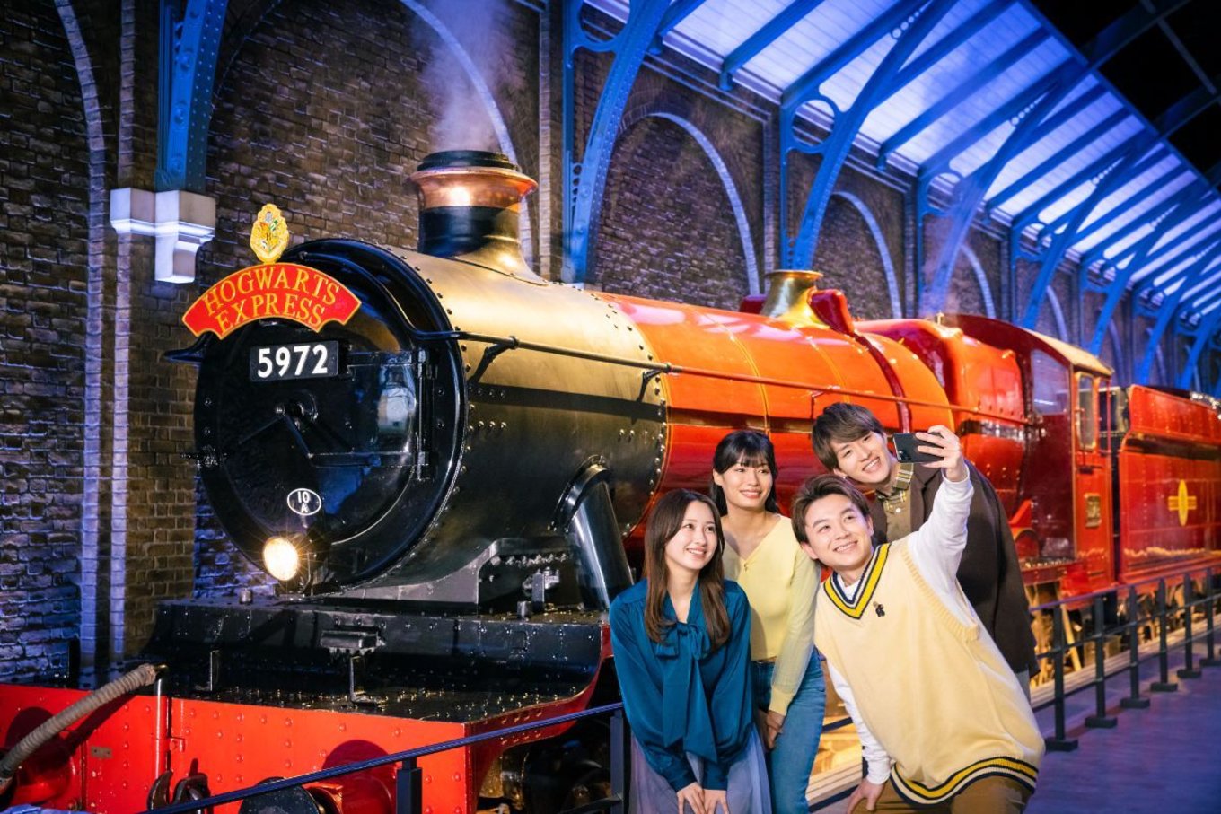 group of people posing in front of hogwarts express