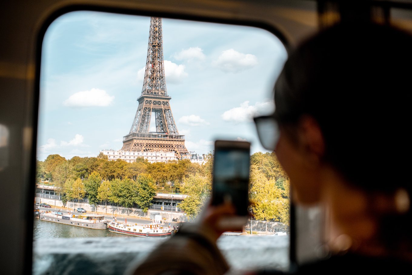 woman taking a photo of the eiffel tower from a train window