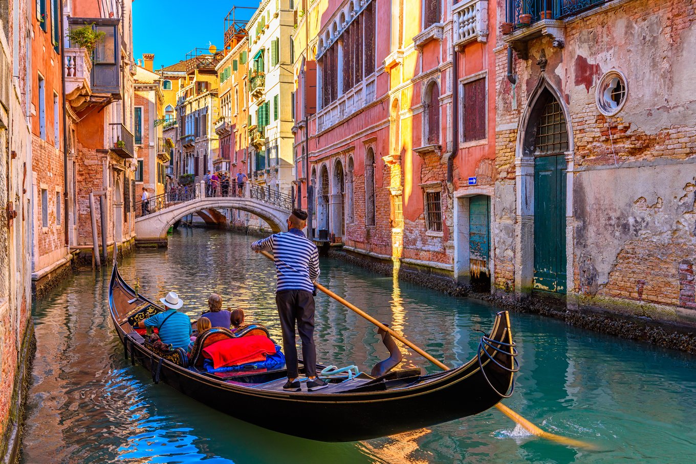 Gondola ride under bridge in vibrant Venice canal with gondolier and passengers