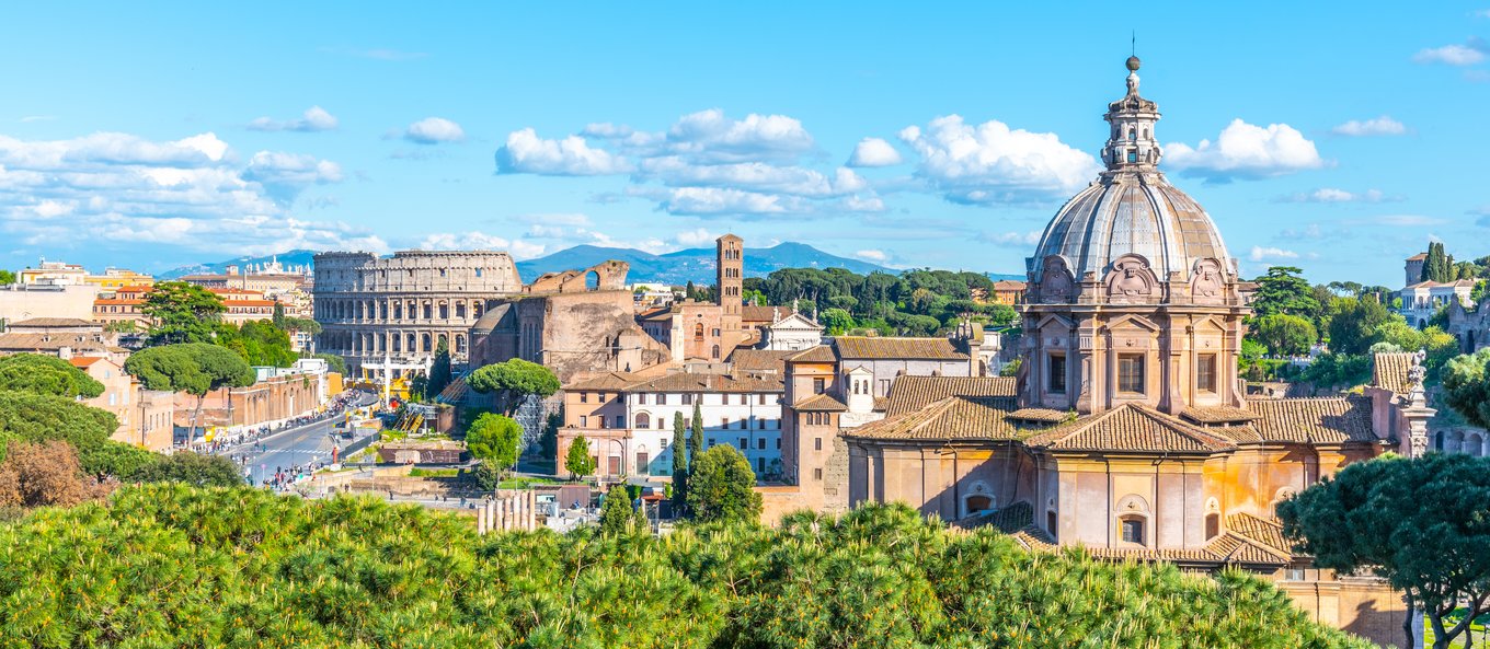 A panoramic view of Rome with the Colosseum and historic buildings under blue skies