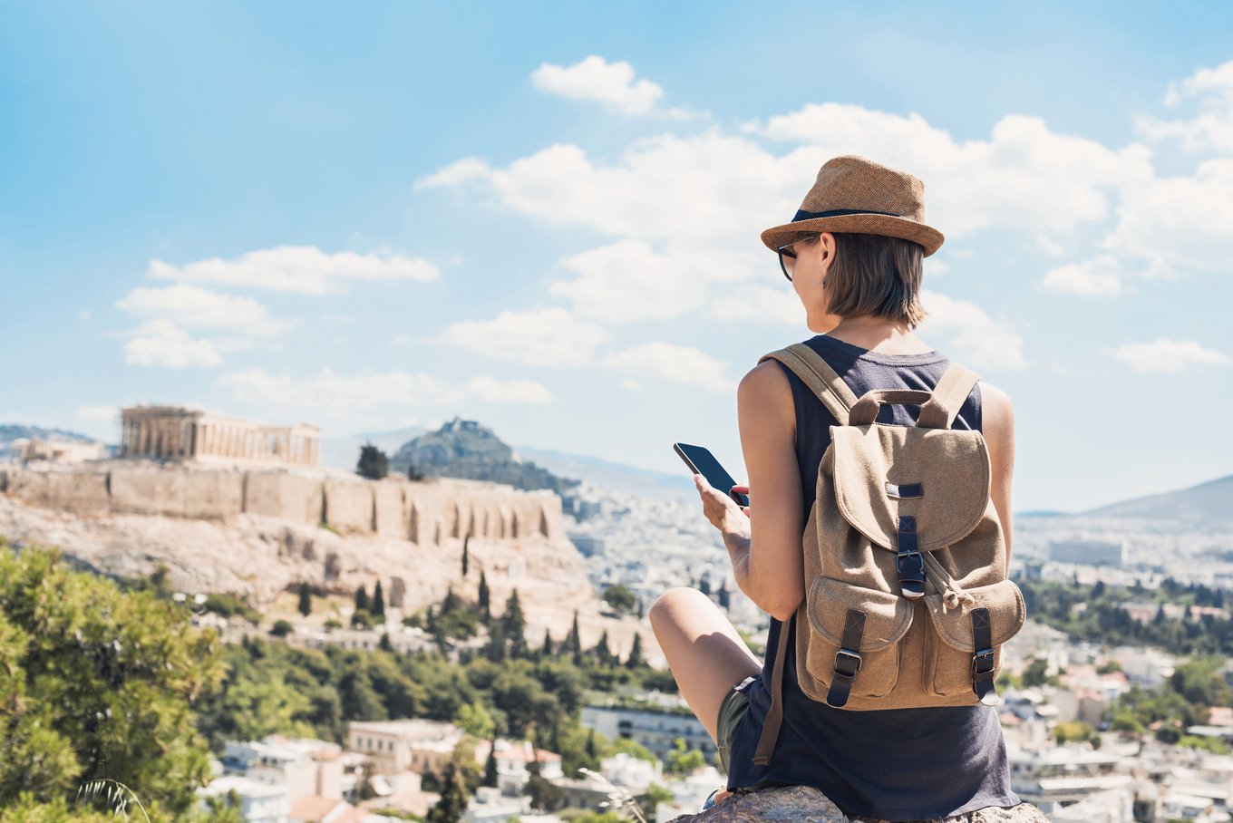 Woman with backpack looking at the Acropolis under bright spring skies