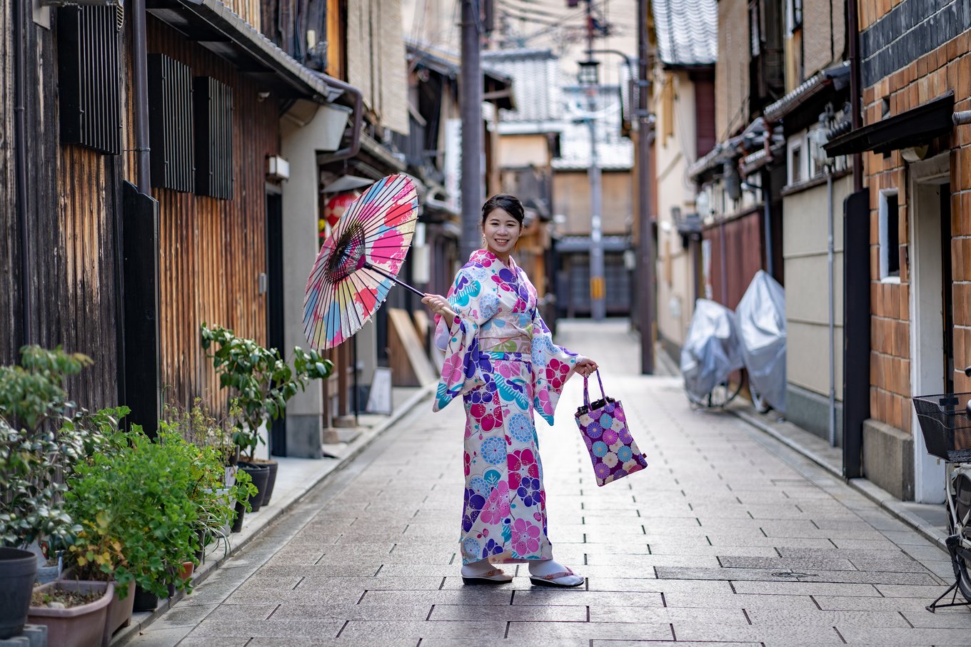 Woman in kimono posing with umbrella on a narrow street in Gion, Kyoto