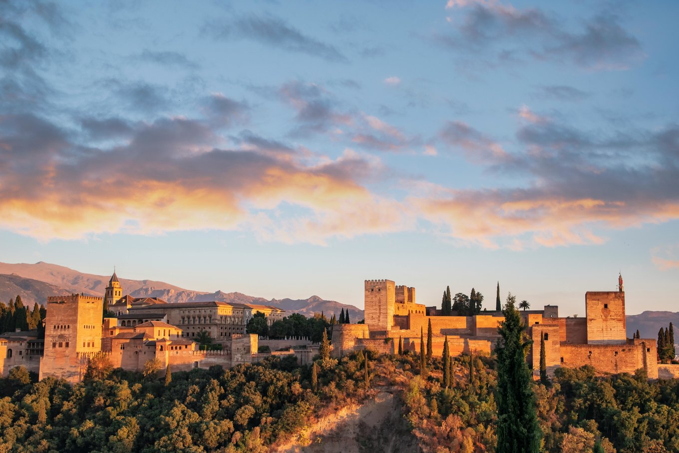 Alhambra palace glowing at sunset with the city of Granada below