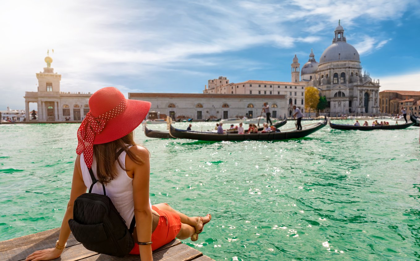 Traveler sitting by the water watching gondolas in Venice, Italy