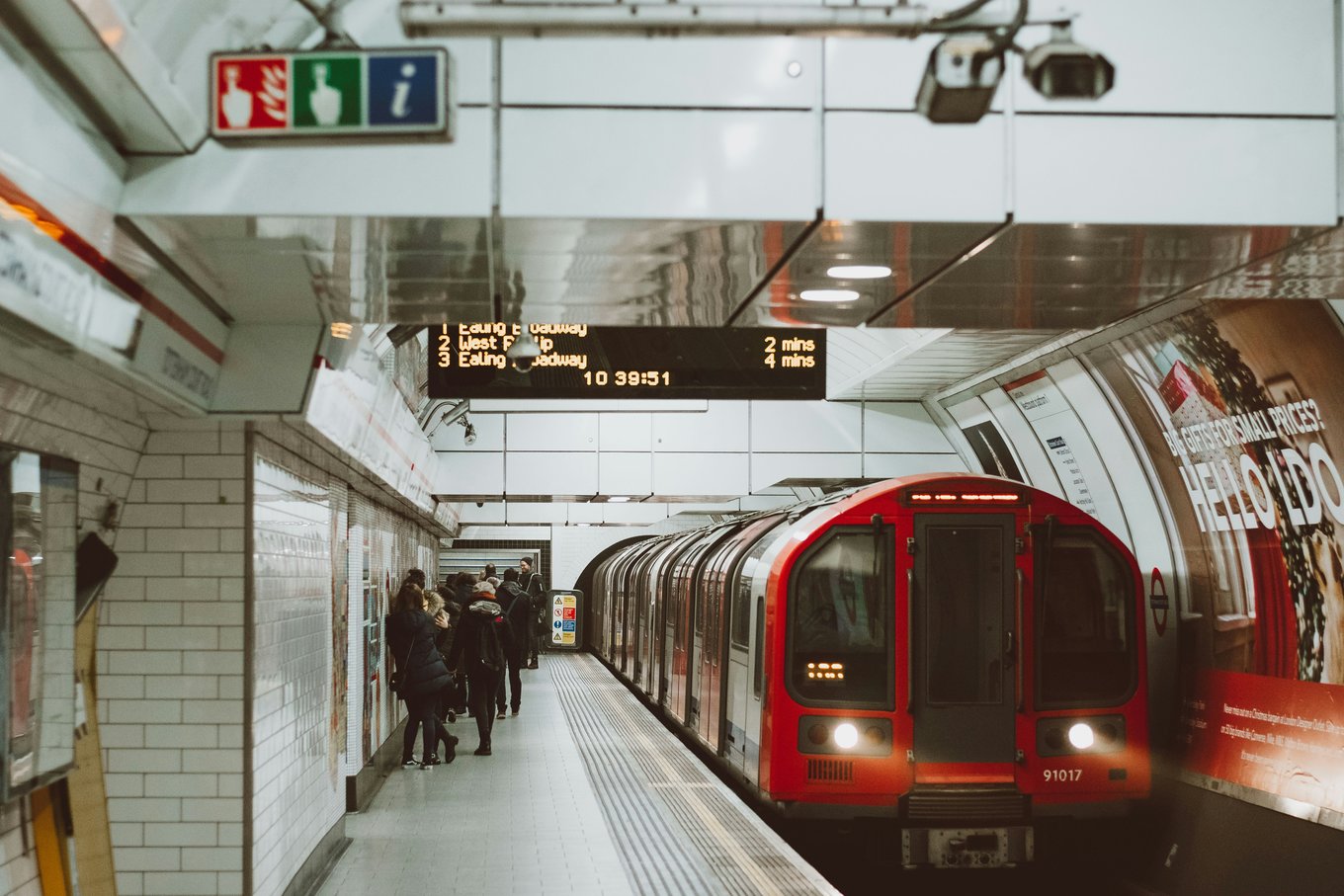 Red London Underground train at a station platform with passengers waiting | Photo Credit: Bruno Souza on Unsplash