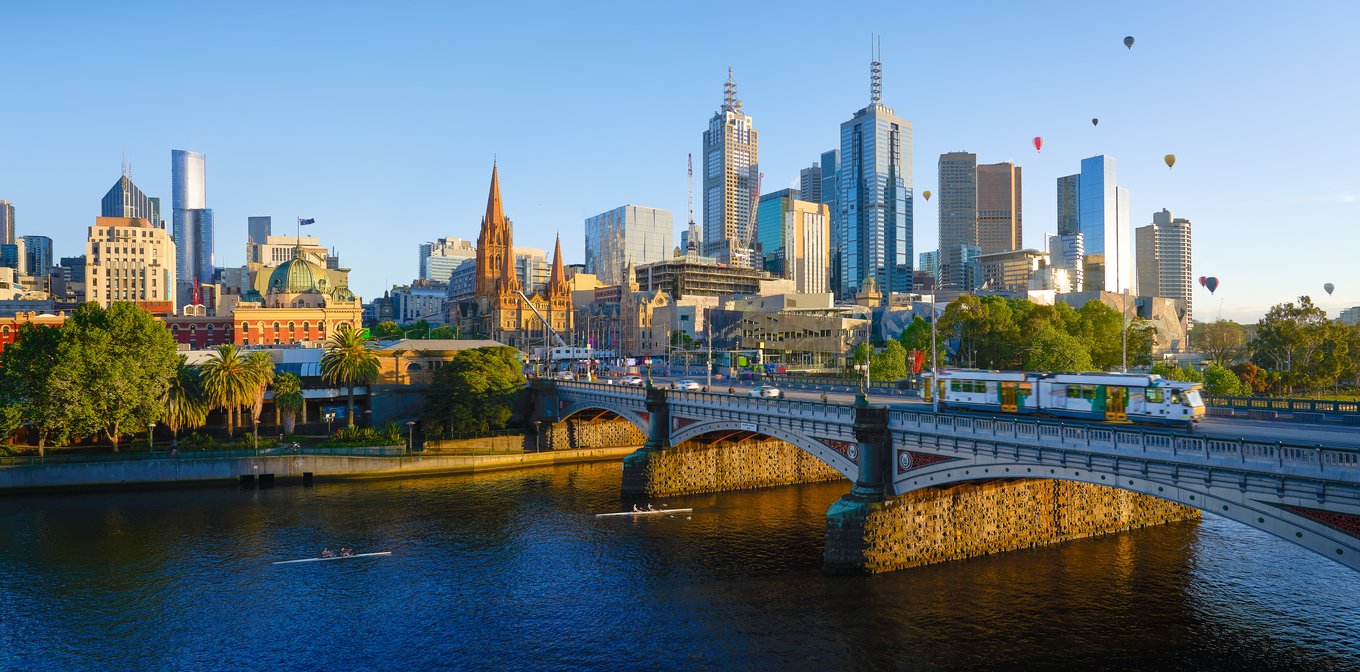 Hot air balloons over Melbourne skyline at sunrise with city landmarks