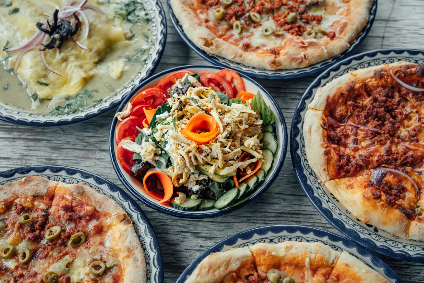 Traditional Italian pizza varieties and fresh salad on wooden table