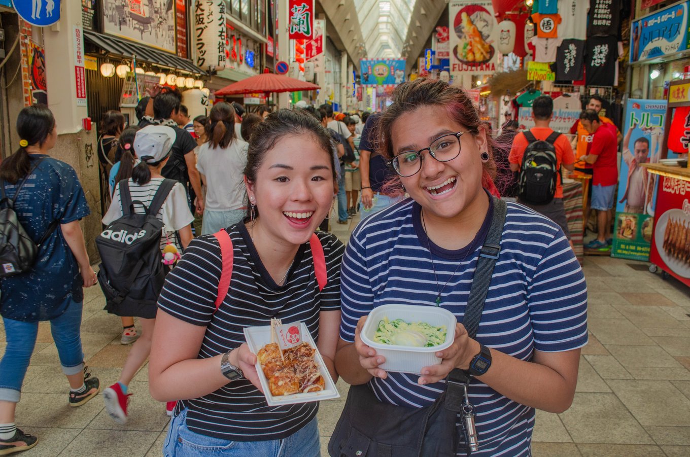 Two girls holding street food in Osaka