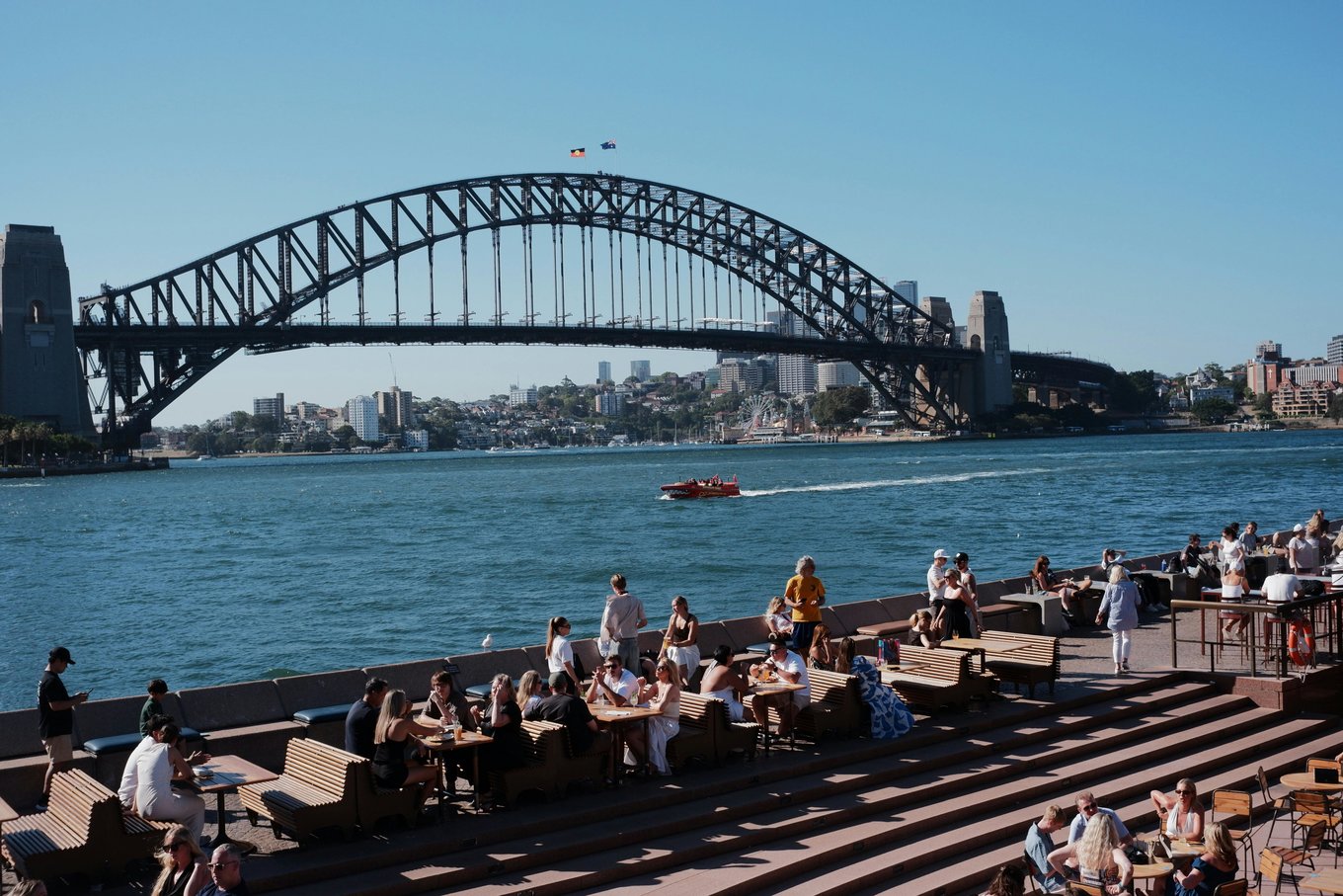 People dining by Sydney Harbour with the Harbour Bridge in the background