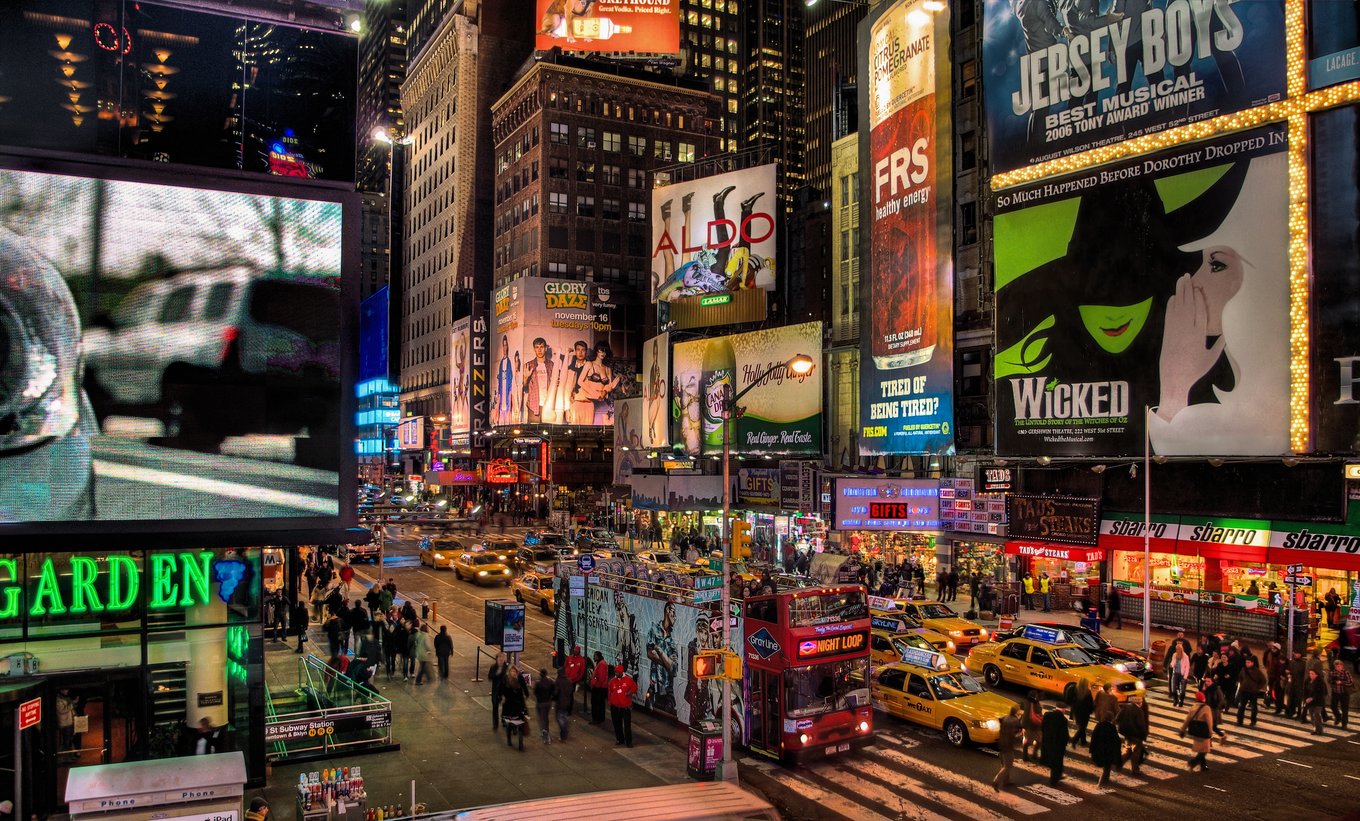 Times Square at night with illuminated billboards, crowds, and yellow taxis in NYC