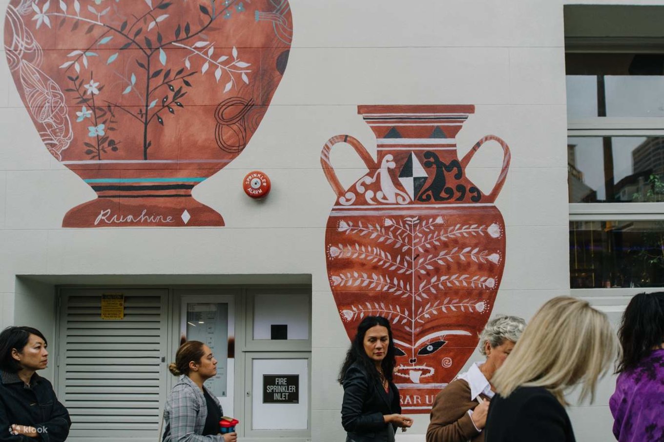 People walking past a Māori-inspired street art mural in New Zealand