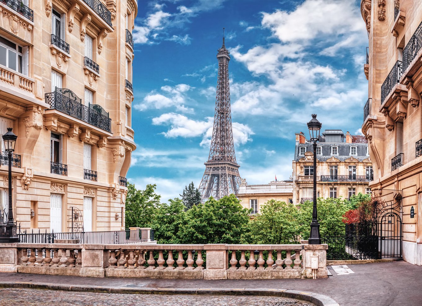 Eiffel Tower seen between historic Paris apartments under blue sky