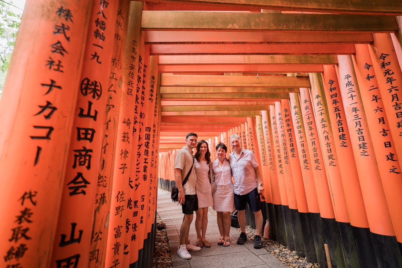 Visitors posing under red torii gates at Fushimi Inari Shrine in Kyoto