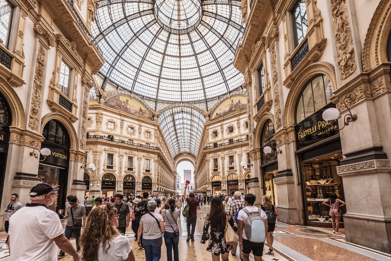 Tourists walking inside Galleria Vittorio Emanuele II glass dome arcade Milan