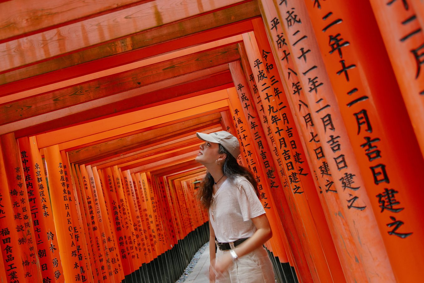 Traveler exploring Fushimi Inari Shrine red torii gates in Kyoto