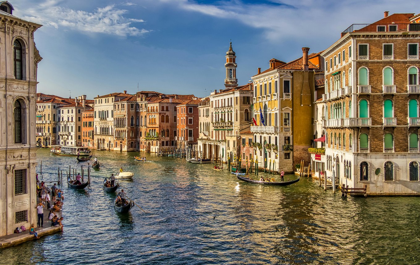 Gondolas cruising along the Venice Grand Canal, bordered by rows of buildings