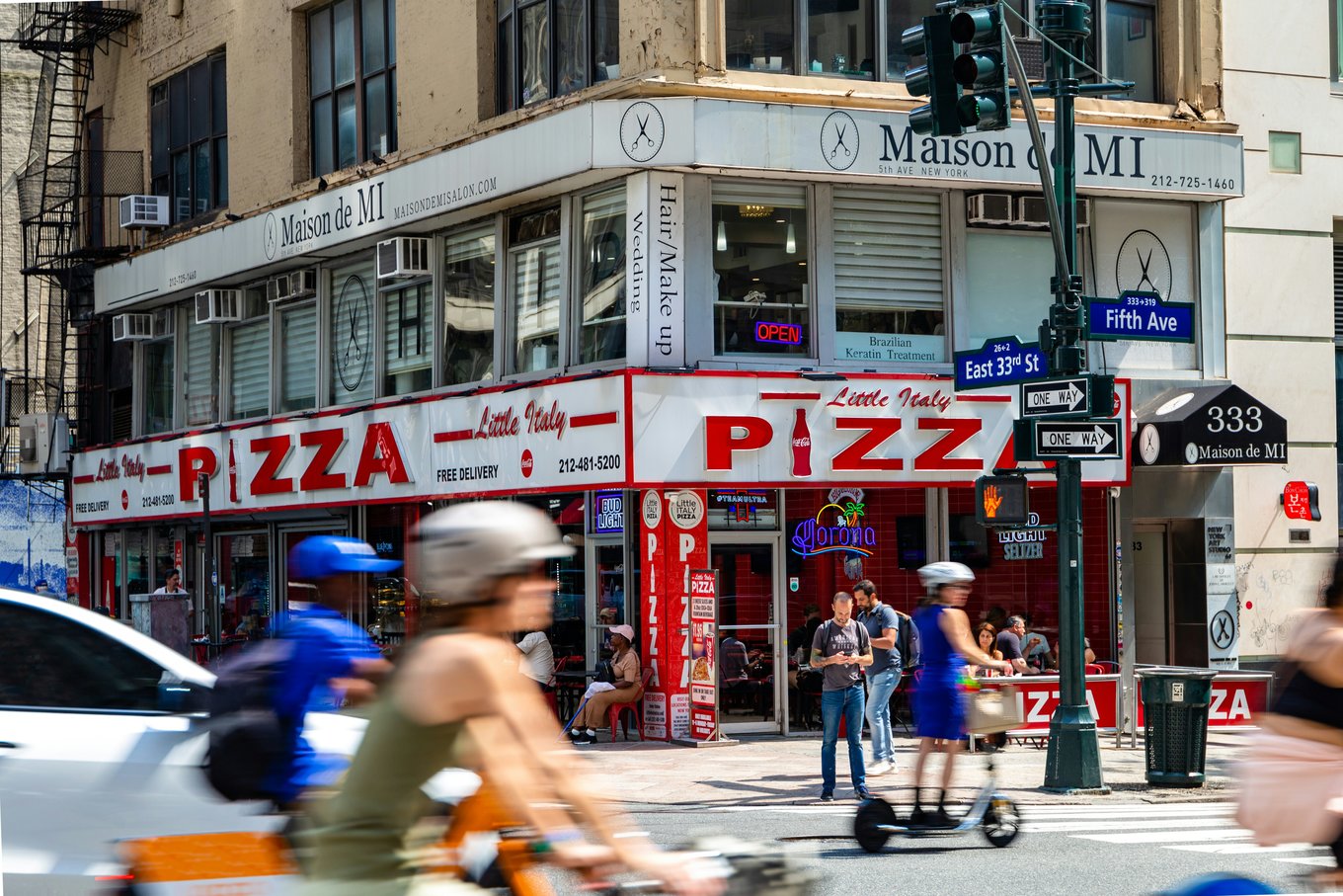 A busy street corner with a pizza restaurant in New York City