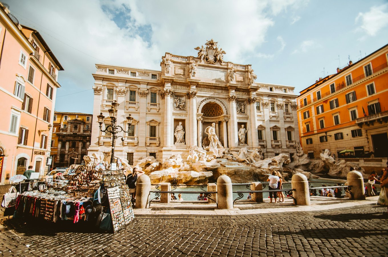 A large fountain structure with detailed sculptures surrounded by colored buildings