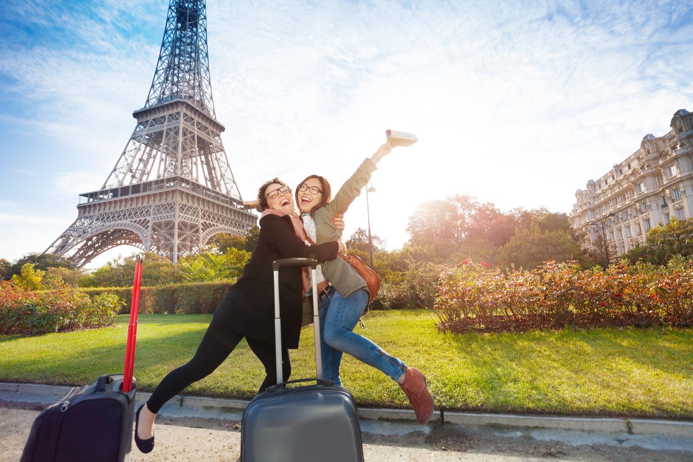 Tourists with luggage celebrating in front of the Eiffel Tower