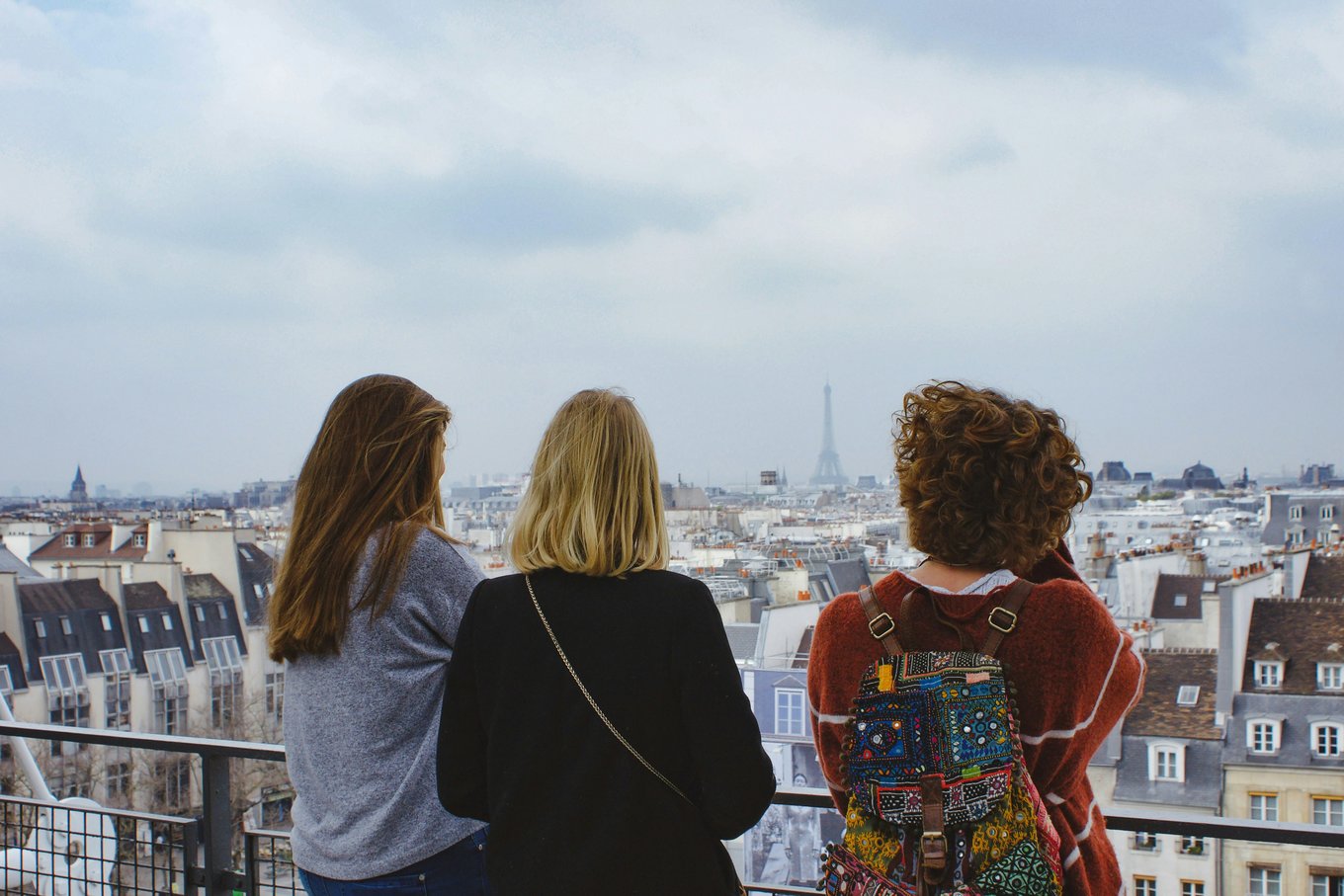 Three young women admiring a view of Paris from above.