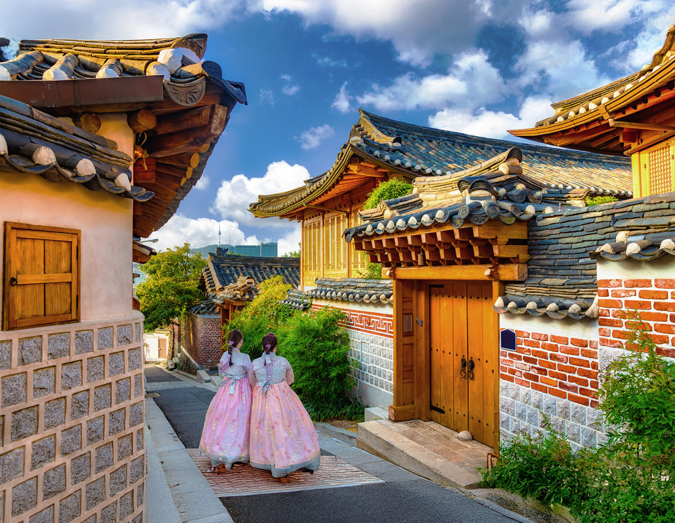 Two people in hanbok walking through a picturesque street in Bukchon Hanok Village