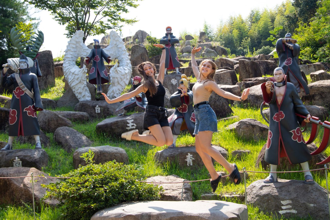 Visitors posing with Naruto anime character statues outdoors