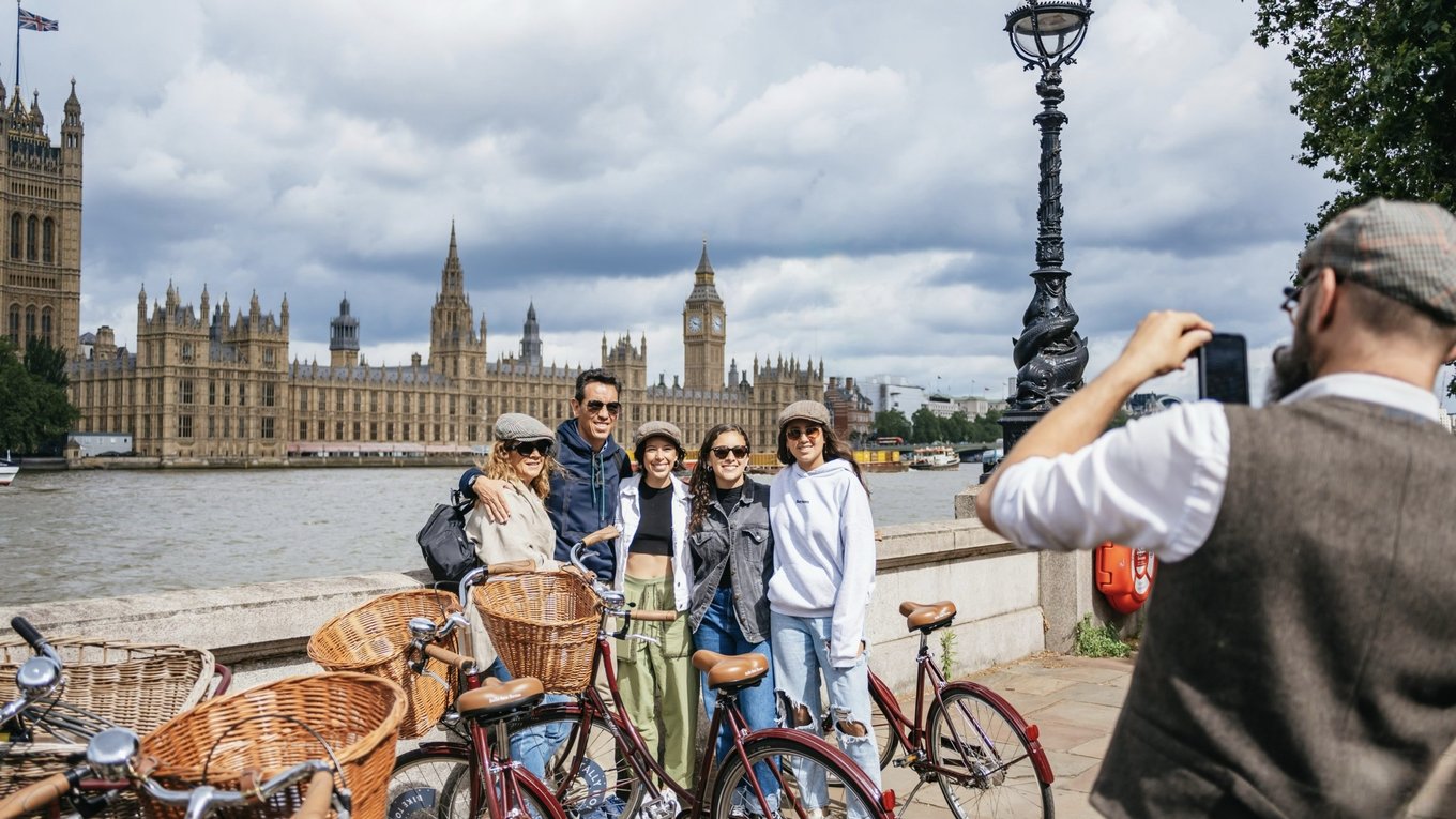 Group on a bike tour posing by the Thames with Big Ben and Houses of Parliament in London