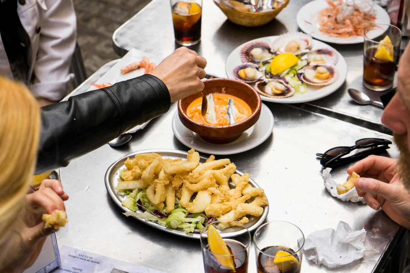 Friends enjoying tapas and drinks around a restaurant table in Seville