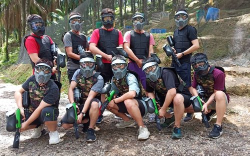 Group of 10 posing with their gear and paint ball gun