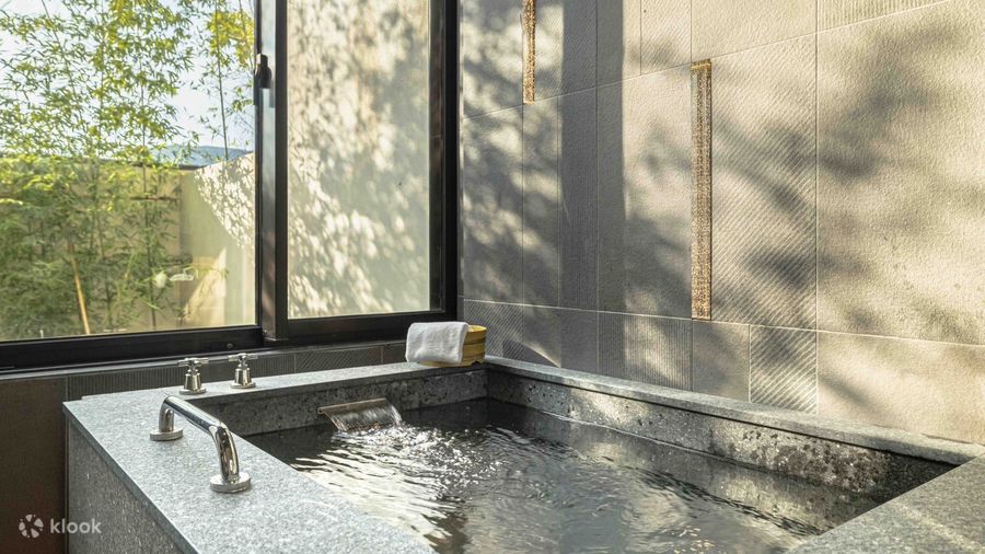 A stone bath filling from the tap at Wellspring by Silks, greenery through the window