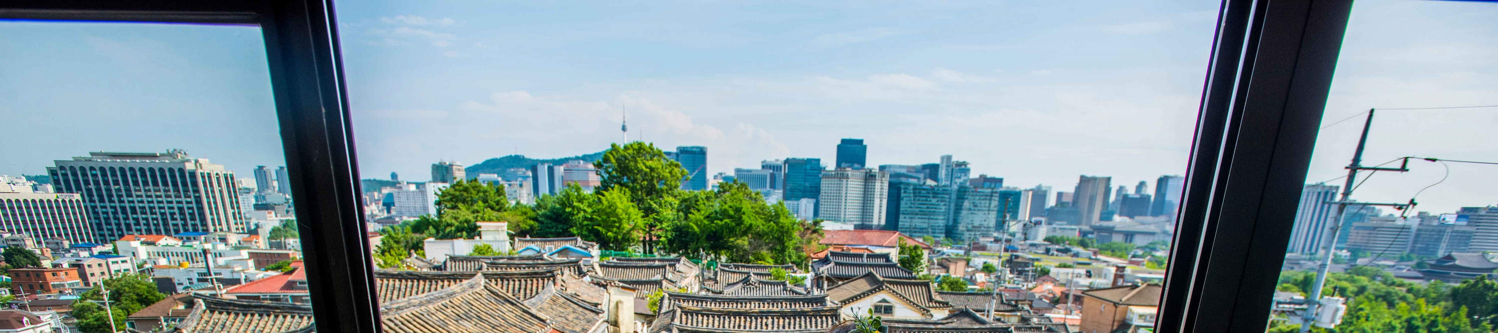 Pemandangan dari Atap Bukchon Hanok Village – tempat pemotretan hanbok terbaik yang menghadap ke atap genteng dan cakrawala Seoul dengan N Seoul Tower.